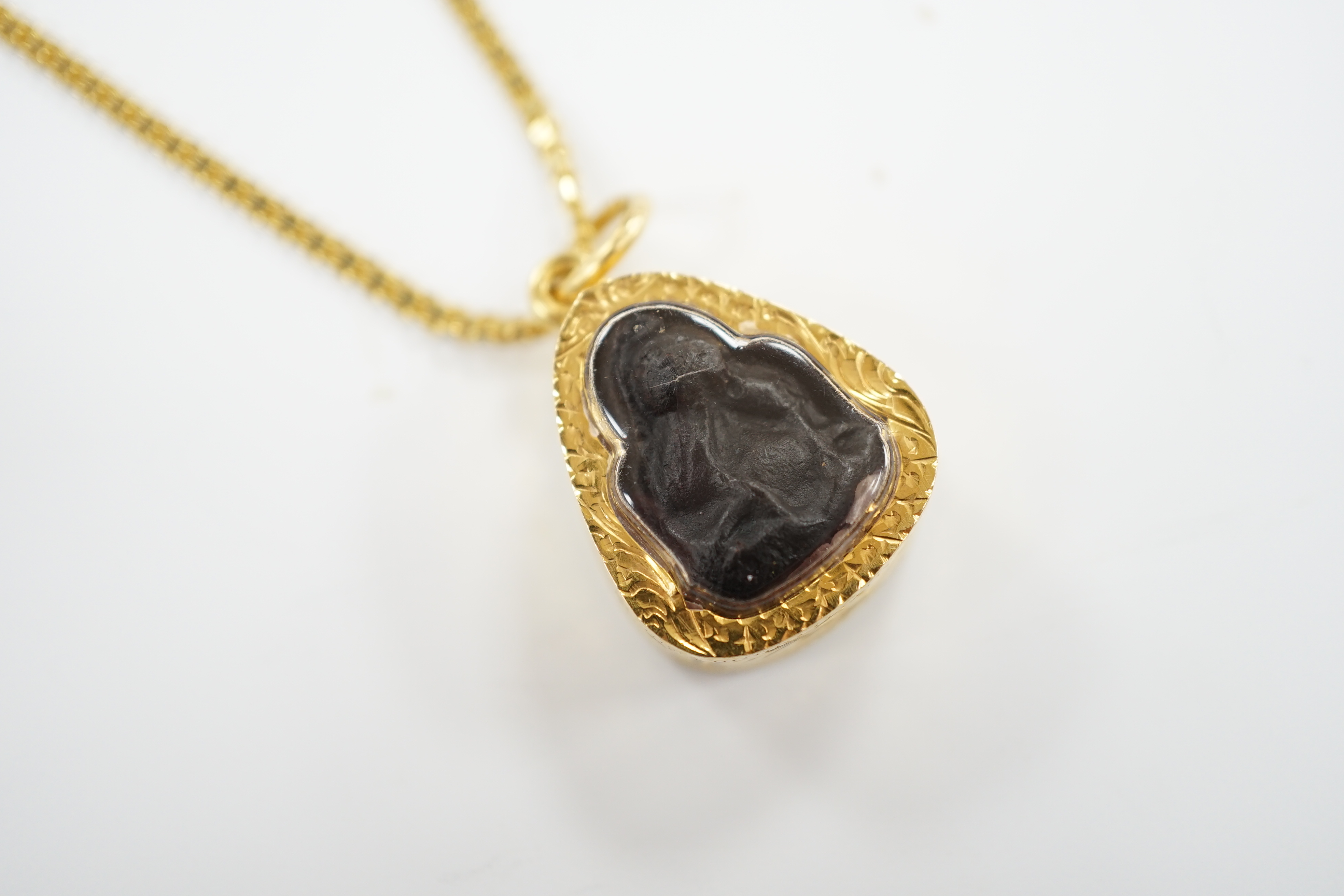 A Thai Phra Pidta Buddha set into a high carat yellow metal pendant mount, Buddha 18mm, on a high carat yellow metal chain, 50cm